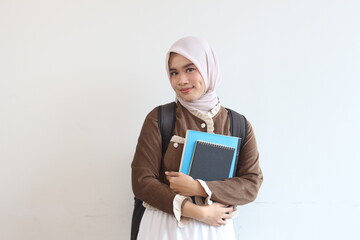 Portrait of a Smiling Muslim Female Student Holding Books Against White Background