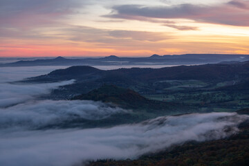 Fototapeta premium Morgenröte mit Nebel im Tal. Ausblick vom Breitenstein ( Ochsenwang ) Schwäbische Alb, Landkreis Esslingen. Am Horizont die drei Kaiserberge - Hohenstaufen, Stuifen und Rechberg. 