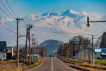 どこまでも続く北海道の一本道と雪化粧の旭岳と紅葉/An endless road in Hokkaido, snow-capped Mount Asahidake and autumn leaves