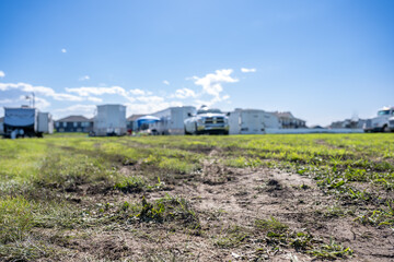 Selective focus on mud and torn up grass in the foreground of a dirt parking lot © Lost_in_the_Midwest
