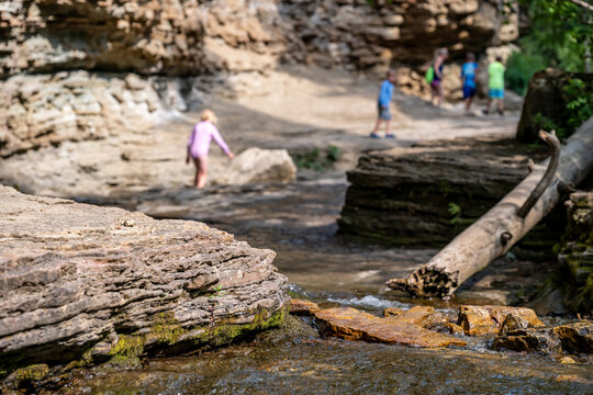 Selective focus on eroded Rock creek with defocused children on the trail to the Devils Bathtub waterfall in Spearfish Canyon, South Dakota