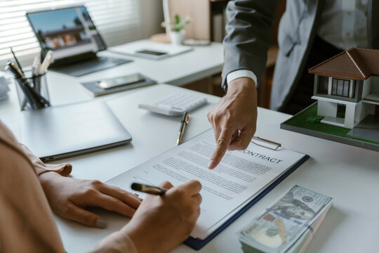 Client signing a contract for a new house, guided by real estate agent in modern office