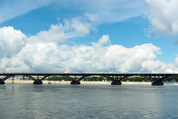 Obraz premium A bridge over a river. A bridge with clouds and a river in the sky. Blue bridge in the nature with blue sky. Blue sky and clouds over the bridge lifestyle in nature.