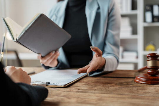Female lawyer holding a book and explaining legal advice to a client during a consultation in a law office