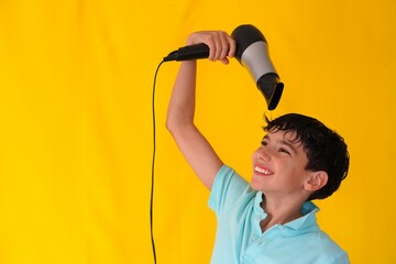 preteen boy drying his hair with a hair dryer