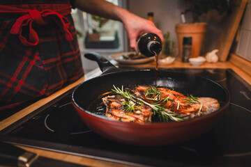 Mann brät sich ein Stück Fleisch zu Hause in der Pfanne