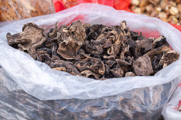 Bulk of dried mushroom product in the plastic sack, there are selling at the local market. Food ingredient object, close-up and selective focus.