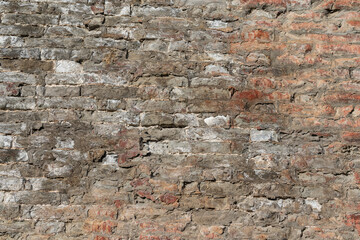 Damaged brick structure surface of the ancient city wall. Building part for texture, close-up.