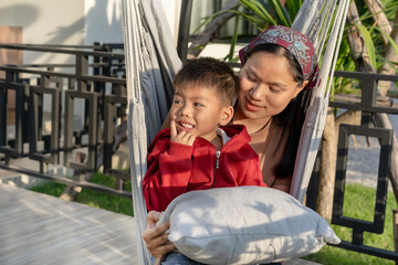 Beautiful Asian mother and her cute little son spend time outdoors. During the weekend together Bright and warm natural background Family lifestyle.