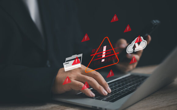 businessman works on a laptop surrounded by red warning icons, symbolizing cybersecurity threats, data security issues, and the urgent need for protection against digital vulnerabilities and breaches. - Powered by Adobe