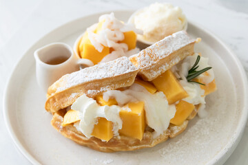 Delicious waffle mango dessert with young coconut and whipped cream.