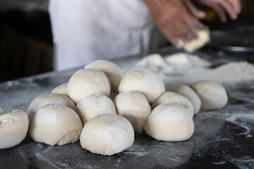Freshly prepared dough balls on a kitchen surface.