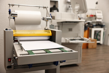 Modern roll laminator with paper indoors. Printing house