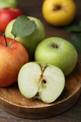 Different ripe apples on wooden table, closeup