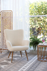 Stylish living room interior with soft white armchair