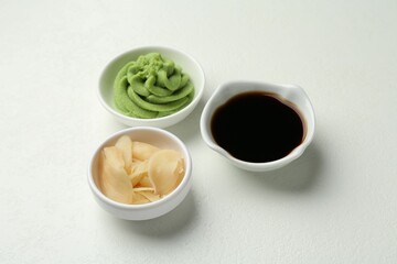 Hot wasabi paste, soy sauce and ginger on light textured table, closeup
