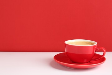 Red cup with coffee on white table. Space for text
