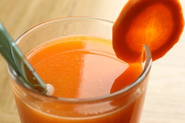 Fresh carrot juice in glass on light table, closeup