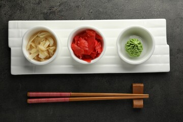 Hot wasabi paste, ginger and chopsticks on grey table, top view
