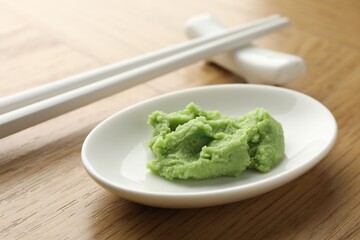 Hot wasabi paste and chopsticks on wooden table, closeup