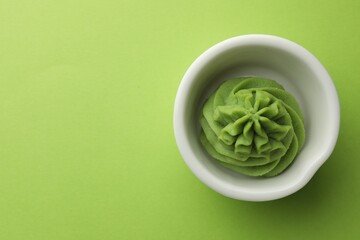 Hot wasabi paste in bowl on green table, top view. Space for text