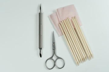 Manicure scissors on a white background, paired with orange cuticle sticks and a pusher.
