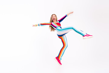 Energetic young woman leaping gracefully in colorful striped outfit on white background, expressing...