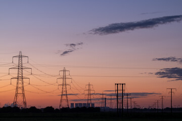 Power lines and distant power station at sunrise