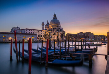 Naklejka premium Gondolas lined up by the Grand Canal at sunset in Venice with historic architecture in view