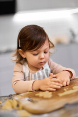 cute little child girl cutting gingerbread cookies with a cookie cutter in kitchen. festive gingerbread cookies