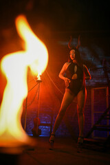 Beautiful asian woman a demon with evil horns posing on a dark background in red lights.