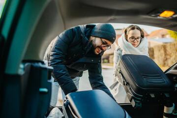 Boyfriend and girlfriend packing suitcases in car preparing to travel	
