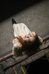 Beautiful young woman in a beige long dress posing on stairs of an old building..