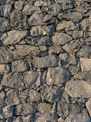 Background of a stacked stone wall of volcanic rock. Vertical shot.
