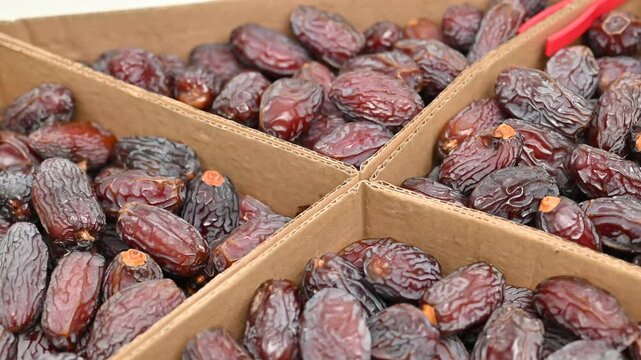 Close-Up of Fresh Dates in Cardboard Boxes. Neatly arranged fresh, ripe dates in a sectioned cardboard box, highlighting healthy, natural dried fruit ready for consumption.

