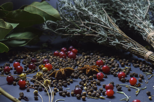 various spices scattered on a dark background with bunches of grass, laurel leaves, berries and other spices for cooking fragrant Eastern and Midwestern food. High quality photo