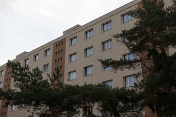 A large apartment building featuring numerous windows and a number of trees situated right in front of it, creating a pleasant view