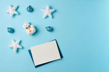 Christmas blank card with balls, stars and teddy bear on a blue background. Space for text. Flat lay, top view