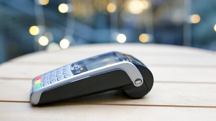 Contactless payment terminal lying on a table in a blurred background