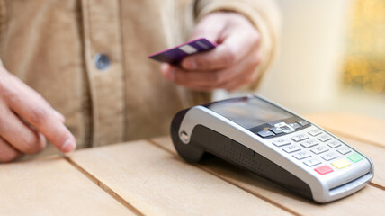 Person paying with contactless credit card at pos terminal