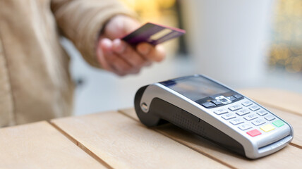 Person paying with contactless credit card at pos terminal