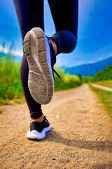 Close-up of a beautiful woman running on a dirt road near stunning mountains