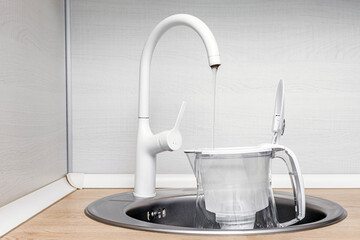water from the kitchen faucet flows into the water filter. water filter in the kitchen