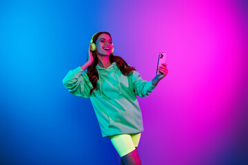 Obraz premium Photo of cheerful pretty lady dressed sweatshirt earphones listening music modern gadget isolated neon pink color background