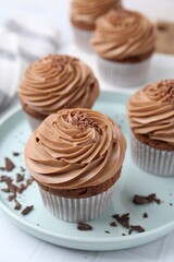 Tasty cupcakes with chocolate cream on white tiled table, closeup