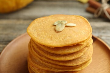 Tasty pumpkin pancakes with seeds on table, closeup