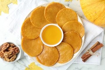 Tasty pumpkin pancakes served on white marble table, flat lay