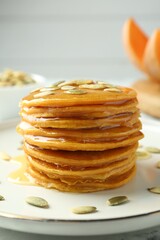 Tasty pumpkin pancakes with seeds on table, closeup