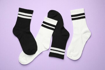 Different soft socks on violet background, flat lay