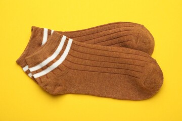 Pair of soft socks on yellow background, top view